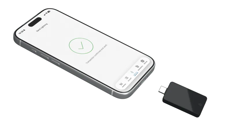 A hardware wallet beside a phone showing a payment