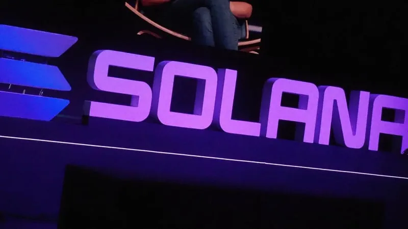 컨퍼런스 무대에서 빛나는 커다란 보라색 Solana 글자와 로고